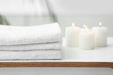 Banyodaki çekmecelerde temiz havlu ve mumlar yığını.