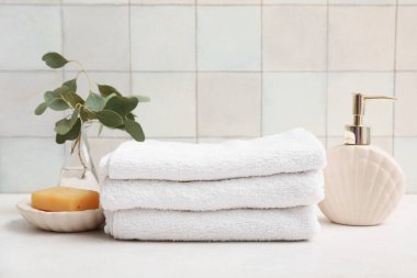 Temiz yumuşak havlu yığını, bir şişe kozmetik ürün ve banyo duvarının yanındaki sabun kalıbı.