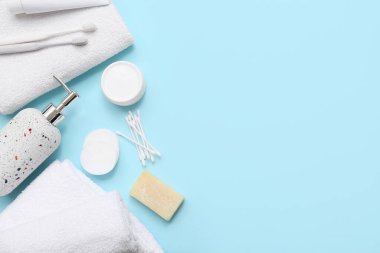 Temiz yumuşak havluyla kompozisyon ve mavi arka planda farklı banyo malzemeleri.