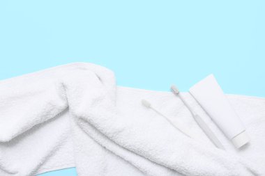 Temiz yumuşak havlu, diş macunu tüpü ve mavi arka planda diş fırçası bileşimi