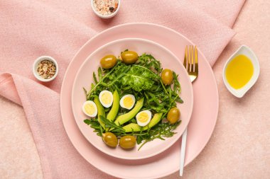 Sağlıklı salata, bıldırcın yumurtası, peçete ve baharatlı pembe grunge arkaplan.