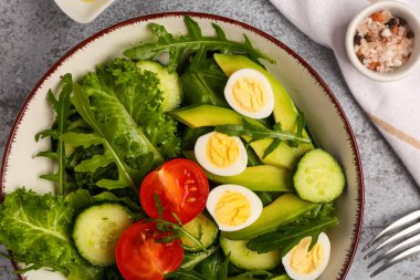 Sağlıklı salata, bıldırcın yumurtası, domates, avokado ve salatalık ve grunge arka planda, yakın plan.