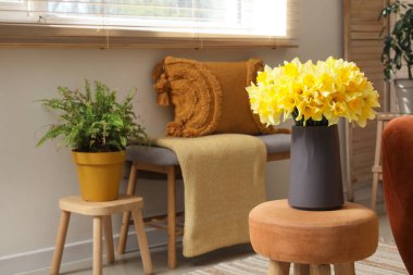 Oturma odasının iç tarafında ekose ve narsist çiçekleri olan rahat bir kanepe.