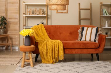 Oturma odasının iç tarafında ekose ve narsist çiçekleri olan rahat bir kanepe.