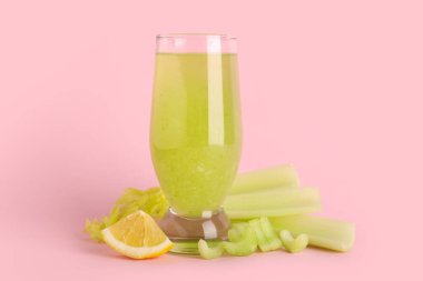 Pembe arka planda kereviz ve limonlu bir bardak taze meyve suyu.