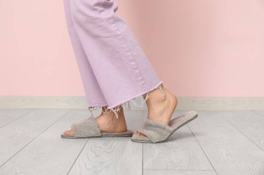 Evde kabarık gri terlikli genç bir kadın var.