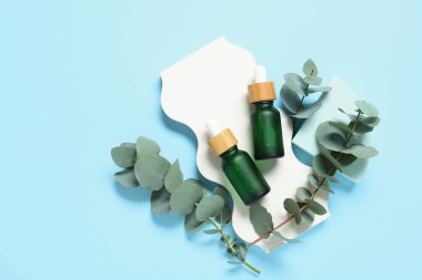 Gerekli yağ şişeleri, alçı tezgahları ve mavi arka planda okaliptüs dalları