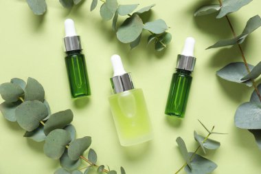 Yeşil arka planda gerekli yağ ve okaliptüs dalları şişeleri, yakın plan