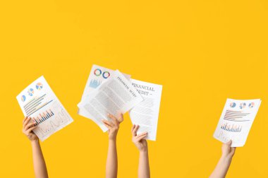 Sarı arkaplanda belgeleri ve grafikleri olan kadın eller