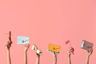 Farklı çantalara sahip kadın elleri ve pembe arka planda topuklu ayakkabılar.