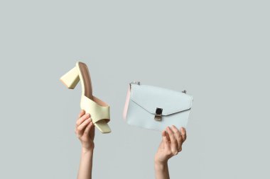 Gri arka planda kadın eli ve topuklu ayakkabı.