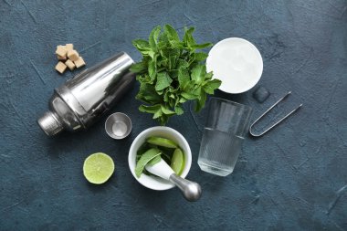 Titretici, ölçü kabı, cam ve mavi arkaplanda mojito malzemeleri.
