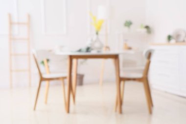 Açık mutfak, yemek masası ve raf üniteleriyle bulanık görünüyor.