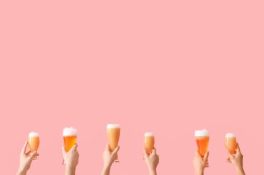 Pembe arka planda bira bardakları tutan bir sürü el