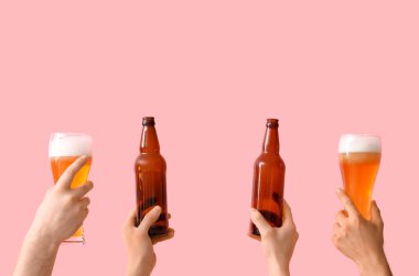 Birçok el pembe arka planda bira ve şişe bardaklarını tutuyor.
