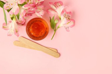 Cam kâse şekerleme macunu, tahta çubuklar ve pembe arka planda çiçekler