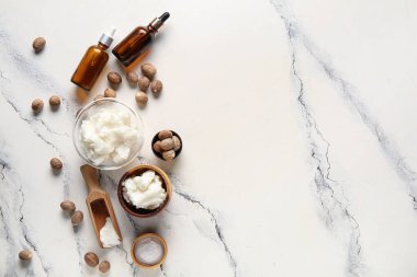 Beyaz arka planda kozmetik yağı ve fındık dolu bir kase Shea yağı.