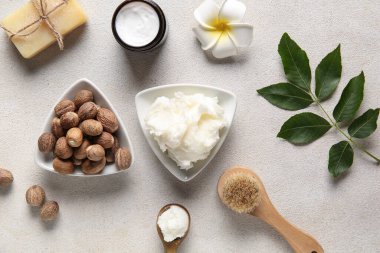 Bir kase tereyağlı sabun, masaj fırçası, tesisat çiçeği ve beyaz arka planda fındık.