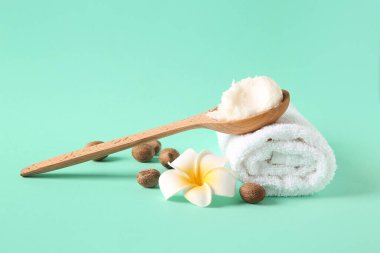 Bir kaşık tereyağı, tesisat çiçeği, havlu ve turkuaz arka planda fındık.