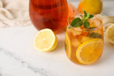 Limonlar ve bir bardak lezzetli soğuk buzlu çay mermer arka planda, yakın plan.