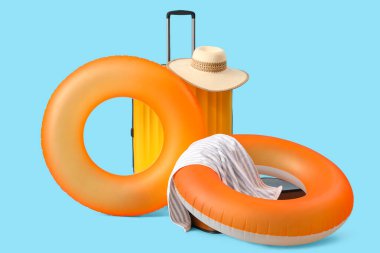 Şişirilebilir halkalar, bavul, havlu ve mavi arka planda şapka. Seyahat kavramı