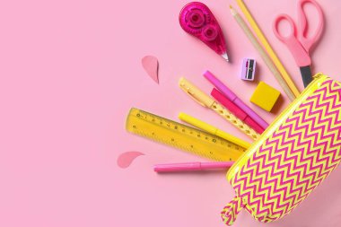 Pembe arka planda farklı kırtasiye malzemesi olan kalem kutusu. Üst görünüm