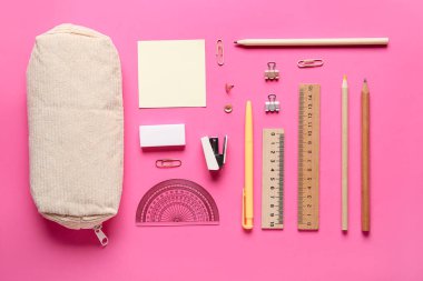 Pembe arka planda farklı kırtasiye malzemesi olan bej kalem kutusu. Üst görünüm