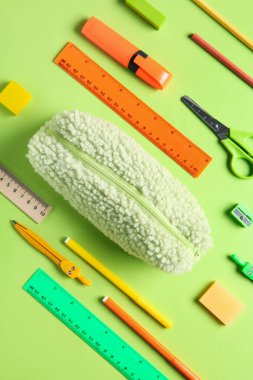 Yeşil arka planda farklı kırtasiye malzemesi olan kalem kutusu. Üst görünüm