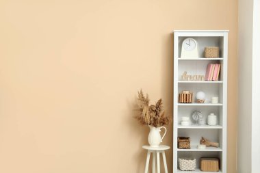 Kitaplar, vazolar ve sepetlerle raflar oturma odasındaki bej duvarın yanında.