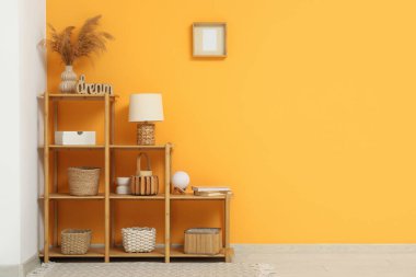 Oturma odasında lamba, kitap ve hasır sepetlerle dizilin.