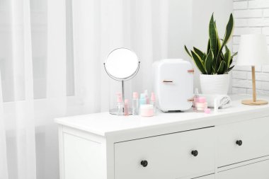 Küçük kozmetik buzdolabı, şişeler ve çekmecelerde kozmetik ürünler.