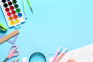 Mavi arka planda keçeli kalemlerle okul malzemeleri. Üst görünüm