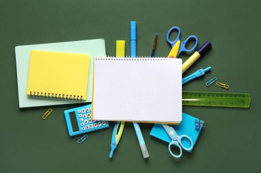 Yeşil arka planda not defterleri olan okul malzemeleri. Üst görünüm