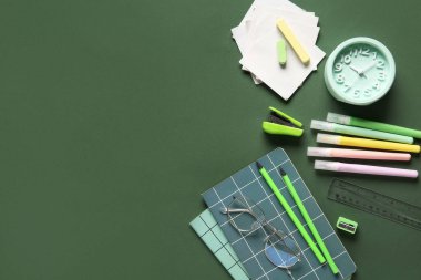 Yeşil arka planda not defteri olan okul malzemeleri. Üst görünüm
