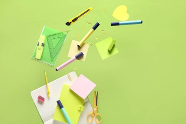 Yeşil arka planda uçuşan farklı okul kırtasiyesi