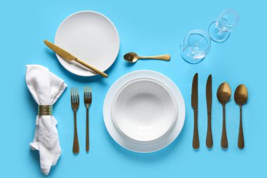 Mavi arka planda altın çatal bıçak seti olan güzel bir masa.