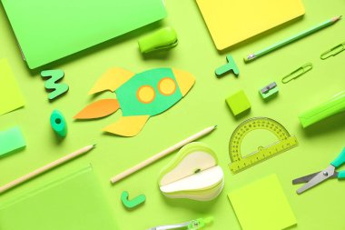 Yeşil arka planda farklı okul kırtasiyesine sahip kağıt roket.