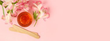 Şekerleme macunu, tahta çubuklar ve pembe arka planda çiçekler ve metin için yeri olan bir kase.