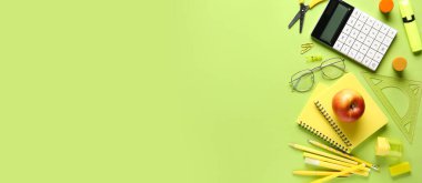 Farklı okul gereçleri ve yeşil arka planda elma, metin için yer, üst görünüm