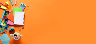 Turuncu arka planda farklı okul malzemeleri, metin için alan, üst görünüm