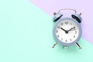 Alarm clock on turquoise and lilac background