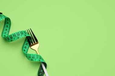 Yeşil arkaplanda yeni ölçüm bandı ve çatal, yakın plan