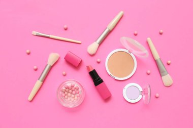 Pembe arka planda makyaj fırçası olan dekoratif kozmetik ürünler.