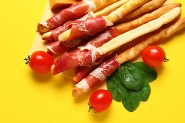 Sarı arka planda pastırmalı lezzetli İtalyan Grissini, yakın plan.