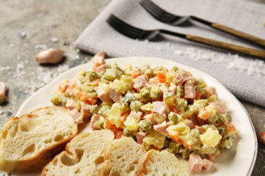 Bir tabak lezzetli Olivier salatası, arka planda ekmek, yakın plan.