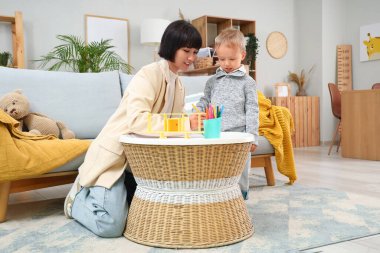 Genç anne ve küçük oğlu evde çizim yapıyorlar.