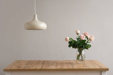 Işık duvarının yanında güzel gül çiçekleri olan vazo