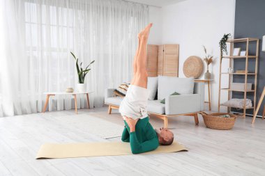 Sportif olgun adam evde yoga yapıyor.