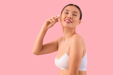 Pembe arka planda makyaj temeli olan genç Asyalı kadın.