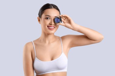 Açık arkaplanda tek gözlü Asyalı genç bir kadın.